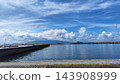 A tranquil harbor and seascape with a blue sky and summer clouds. 143908999