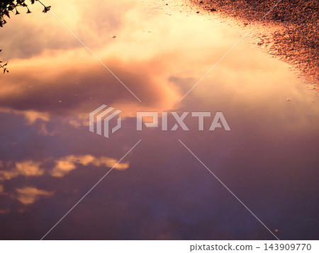夕陽西下,天空和雲彩在瀝青水坑上映出奇幻的倒影。 夕陽西下,天空和雲彩在瀝青水坑上映出奇幻的倒影。 143909770