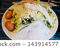 Top view food preparation featuring healthy food on a round plate. Eggs, fiber-rich vegetables, and low-carb glass noodles with delicate enoki mushrooms. Fresh ingredients of hot pot in Thailand 143914577