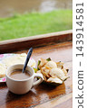 Delicious Thai coconut pudding or coconut pancake is traditional dessert in Thailand. A ceramic cup of hot coffee and bread with fresh butter in white dish is breakfast on wooden table of resort 143914581