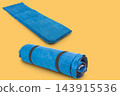 Blue self inflating camping mat unrolled and rolled on yellow background 143915536