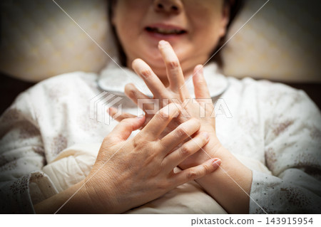 中老年婦女因臥室乾燥而出現手部搔癢的症狀。 中老年婦女因臥室乾燥而出現手部搔癢的症狀。 143915954