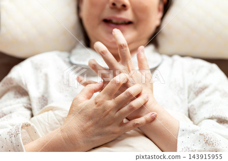 中老年婦女因臥室乾燥而出現手部搔癢的症狀。 中老年婦女因臥室乾燥而出現手部搔癢的症狀。 143915955