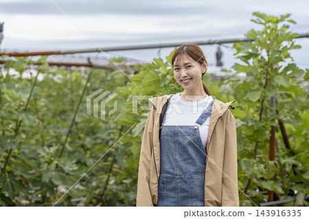 一位農婦在無花果園裡微笑著,直視鏡頭。 一位農婦在無花果園裡微笑著,直視鏡頭。 143916335