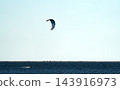 Lonely kitesurfer gliding across wide open sea horizon 143916973