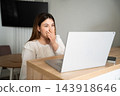 Young woman covering her mouth while viewing a laptop at home. Media literacy online content awareness and digital wellbeing 143918646