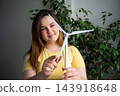 Young woman assembling a small wind turbine model in a bright indoor learning space. STEM education renewable energy and clean technology 143918648