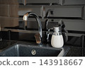 Modern chrome kitchen faucet above a dark composite sink with soap dispenser and black tile backsplash. Kitchen renovation sink and faucet upgrades 143918667