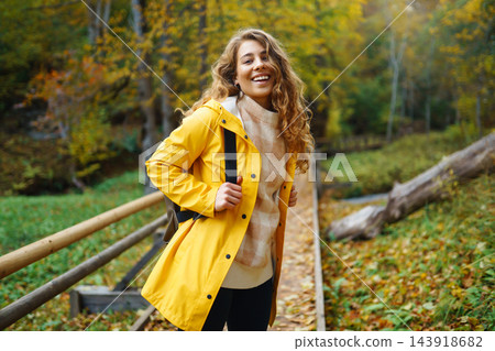 Active woman with backpack enjoys hiking on wooden stairs in autumn forest. Active woman with backpack enjoys hiking on wooden stairs in autumn forest. 143918682