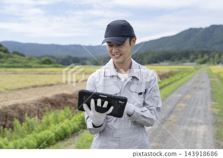 一位農民正在用平板電腦查看農作物的生長情況。 一位農民正在用平板電腦查看農作物的生長情況。 143918686