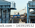 Crane at industrial recycling facility Magdeburg hafen large scrap metal pile beside scrap piles rail tracks port machinery. Blue metal structures frame working yard under clear sky in urban Germany 143919532