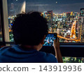 一名男子正在拍攝摩天大樓的夜景。 143919936