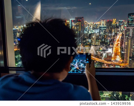 一名男子正在拍攝摩天大樓的夜景。 一名男子正在拍攝摩天大樓的夜景。 143919936