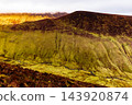 Scenic valley view featuring rugged hills covered in green grass and dark shrubs under a soft morning sky. 143920874