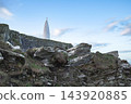 The landscape features a stark white conical tower, a prominent red sphere on its peak, and a rugged, overgrown rocky outcrop. 143920885