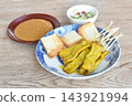grilled pork satay stabing wooden stick couple bread dipping with sweet peanut sauce and pickled vegetable Indonesian food on plate 143921994