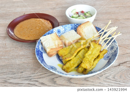 grilled pork satay stabing wooden stick couple bread dipping with sweet peanut sauce and pickled vegetable Indonesian food on plate 143921994