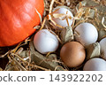 White and brown fresh eggs with dry hay straw. Nature background. Chicken egg in carton box for cooking healthy food. Bio organic eggs on the farm. 143922202