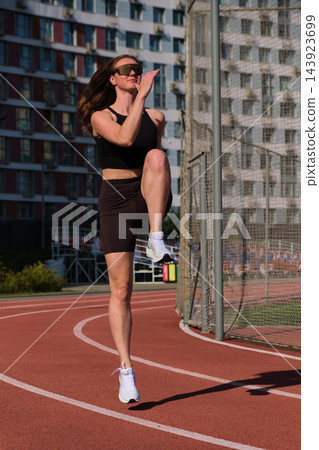 A confident adult lady moves forward with arms active and knees soft on the running track before training 143923699