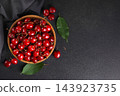 Fresh red ripe sweet cherries in wooden bowl with green leaves on black background with copy space 143923735