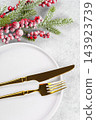 Christmas table setting with gold cutlery on white plate with spruce branch on light gray background 143923739