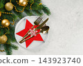 Festive Christmas table setting, dinnerware. White plate and gold cutlery in red star shaped holder 143923740
