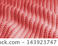 Soft red knitted sweater texture with chunky yarn and raised stitches, waves and gentle folds 143923747