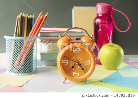 A workspace with school supplies and an alarm clock for studying. School supplies and study materials on a desk. "Back to school" concept. A workspace with school supplies and an alarm clock for studying. School supplies and study materials on a desk. "Back to school" concept. 143923839