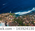 Ocean coastline with village and surfing waves on Nusa Ceningan, drone view 143924130