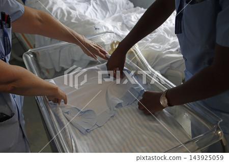 Nurses preparing a hospital cot for a newborn baby 143925059