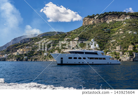 View of beautiful Amalfi town, Campania, Italy. Amalfi coast is most popular travel and holiday destination in Europe. Amalfi cityscape on coast line of mediterranean sea - big yacht View of beautiful Amalfi town, Campania, Italy. Amalfi coast is most popular travel and holiday destination in Europe. Amalfi cityscape on coast line of mediterranean sea - big yacht 143925604