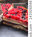 Glossy berry cake slices gleaming on a dark serving tray 143926048