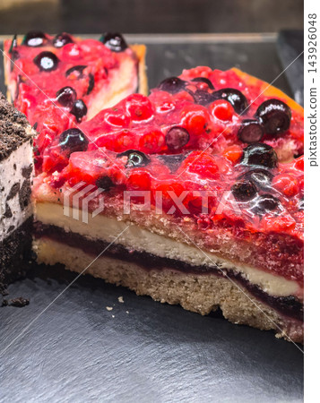 Glossy berry cake slices gleaming on a dark serving tray Glossy berry cake slices gleaming on a dark serving tray 143926048
