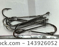 Polished steel fishing hooks resting in a quiet row 143926052