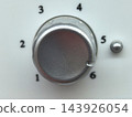 Metal dial rests between numbered settings on a white panel 143926054