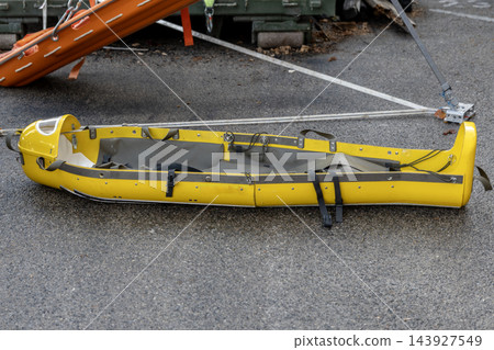 Yellow rescue stretcher lying on asphalt with securing straps Yellow rescue stretcher lying on asphalt with securing straps 143927549