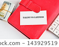 A card reading talent versus laziness rests on a red planner beside cash and a calculator on a desk, with no time of day shown 143929519