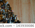 Colorful polished river pebbles arranged at the corner of wooden background  143930086