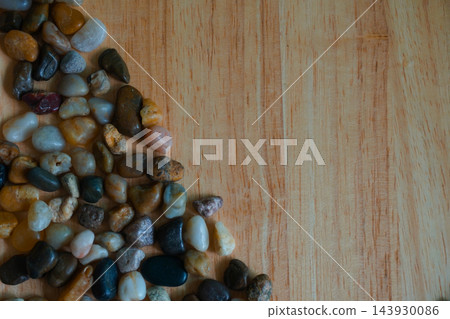Colorful polished river pebbles arranged at the corner of wooden background Colorful polished river pebbles arranged at the corner of wooden background 143930086