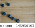 Fresh ripe blueberries scattered on wooden tray  143930103