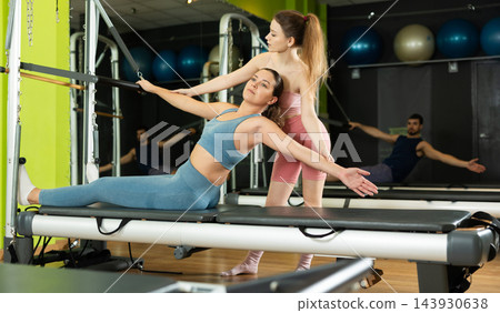 Female trainer helping young woman with abdominal press exercise Female trainer helping young woman with abdominal press exercise 143930638