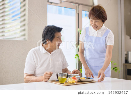 一位老年男性在養老院用餐,一位資深女性工作人員正在為他服務。 一位老年男性在養老院用餐,一位資深女性工作人員正在為他服務。 143932417