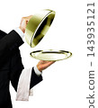 Waiter in black suit opening a golden platter dome with service towel 143935121