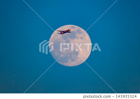 一張長焦照片捕捉到一架全日空飛機在冬日黃昏的滿月之上，於本木碼頭緩緩升空，在夕陽的映照下泛著深紅色的光芒。 143935324