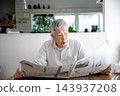 Japanese senior man reading newspaper at home 143937208