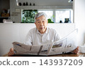 Japanese senior man reading newspaper at home 143937209