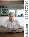 Japanese senior man reading newspaper at home 143937210