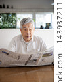 Japanese senior man reading newspaper at home 143937211