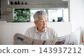 Japanese senior man reading newspaper at home 143937212