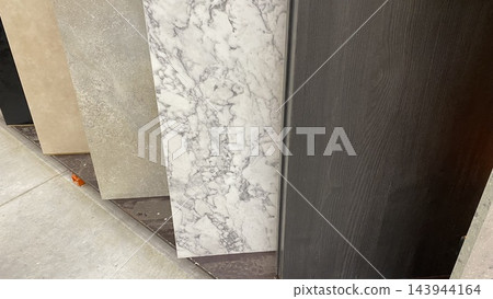 Large decorative wall panels with marble, stone and wood textures displayed vertically at home improvement store Large decorative wall panels with marble, stone and wood textures displayed vertically at home improvement store 143944164